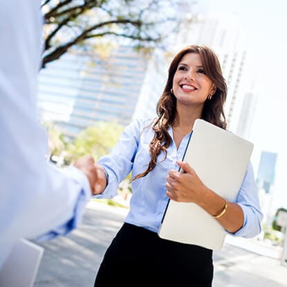 women shaking a hand with papers in her hand